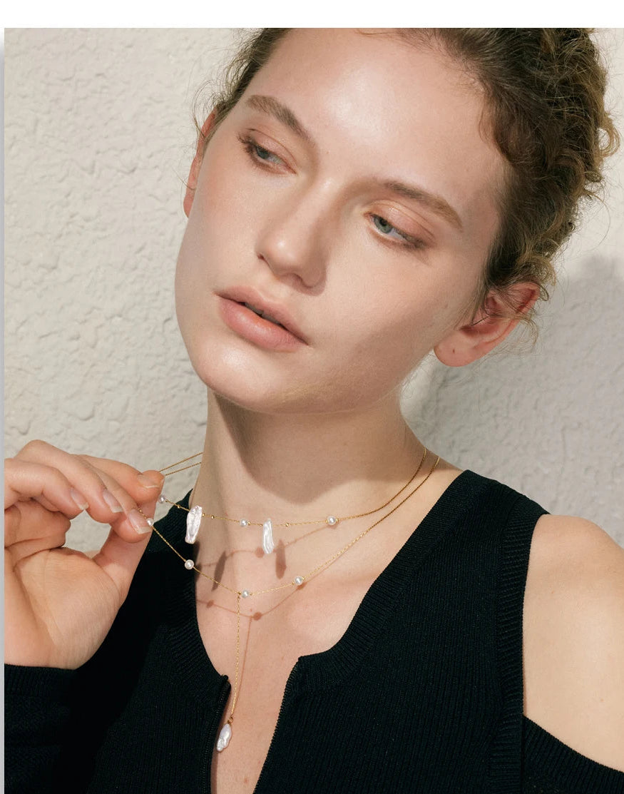 Woman wearing a delicate necklace with a textured wall background